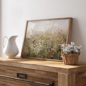 Vintage Spring wall art wildflower field landscape painting art print displayed in an antique frame, featuring pink and beige wildflowers up close. This Spring decor can also be Easter decor. The painting features intricate brushwork and colors. The shop name Lexington Prints is written below.