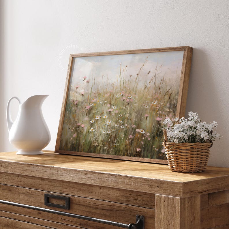 Vintage Spring wall art wildflower field landscape painting art print displayed in an antique frame, featuring pink and beige wildflowers up close. This Spring decor can also be Easter decor. The painting features intricate brushwork and colors. The shop name Lexington Prints is written below.