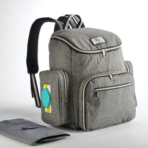 May include: A grey diaper bag backpack with multiple compartments and a changing mat. The bag has a top handle, padded shoulder straps, and a front pocket with a wipe dispenser. The bag has a white trim and gold zips.