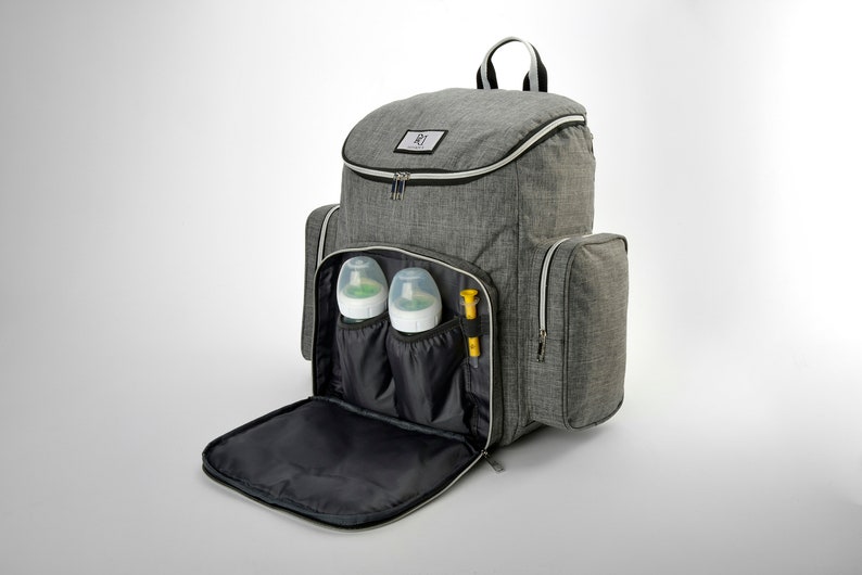 May include: A grey diaper backpack with multiple compartments, including two side pockets and a front flap. The backpack contains two baby bottles and a yellow item. The top of the bag has a zip closure and a handle.