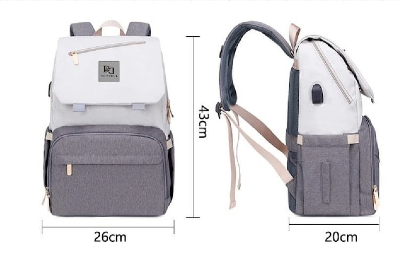 May include: A gray and white diaper bag backpack with a zippered pocket on the front. The bag has a large main compartment and a smaller pocket on the front. The bag is 26 inches wide, 20 inches deep, and 43 inches tall.