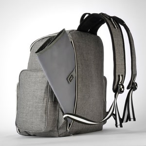 May include: Grey backpack with a changing mat. The backpack features multiple pockets and a zip closure. The shoulder straps are black and white striped. The changing mat is grey and has the letters "D&D" on it.