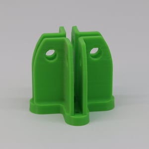 May include: A bright green plastic connector with four sides and a hole in each side. The connector has a flat base.