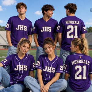 May include: A group of purple jerseys with white trim and lettering. The jerseys feature the text JHS on the front, the number 21 on the sleeves, and some display the name MORREALE with the number 21 on the back. The jerseys are worn with blue jeans.