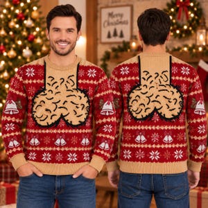 May include: A red and tan long-sleeve knit jumper featuring a repeating pattern of white snowflakes and bells. The centre of the chest displays a large, textured, beige-coloured graphic of testicles outlined in black yarn against a tan panel.