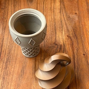 May include: A brown ceramic ice cream cone with a white ceramic ice cream scoop on top. The ice cream cone is sitting on a wooden surface.