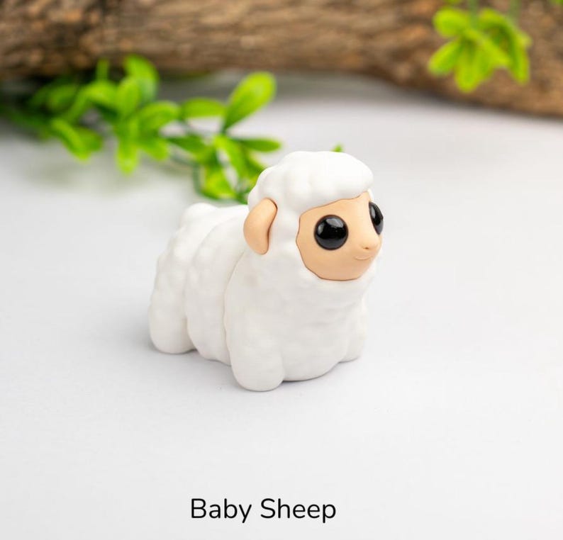 Puede incluir: Figura de oveja beb&eacute; blanca con grandes ojos negros y orejas marrones. La oveja est&aacute; hecha de un material liso. El texto "Baby Sheep" est&aacute; impreso debajo.