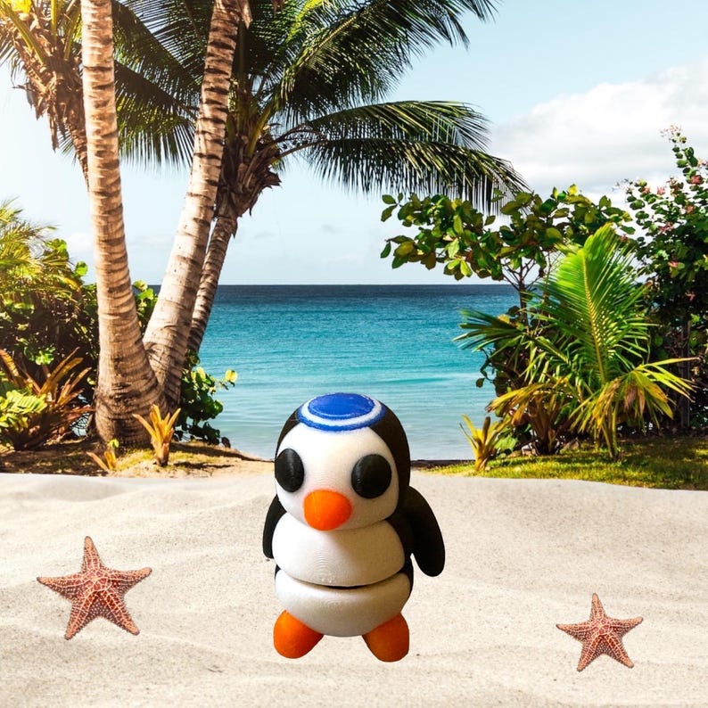 May include: A white and black penguin figurine with a blue hat, standing on a sandy beach with two starfish. The penguin has black eyes, an orange beak, and white and black wings.