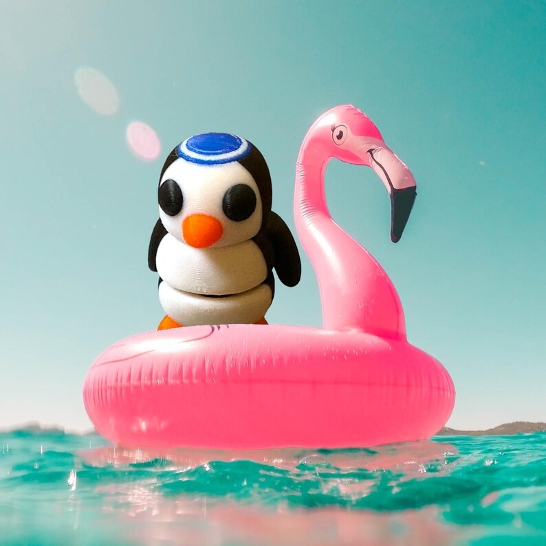 May include: A pink inflatable flamingo pool float with a penguin figurine sitting on top. The penguin is wearing a blue and white hat.