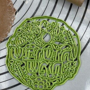 May include: Green plastic cookie cutter with a floral design and the words "Happy Summer" in a decorative font.