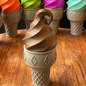May include: A chocolate ice cream cone with a swirl of chocolate ice cream on top. The cone is sitting on a wooden surface.
