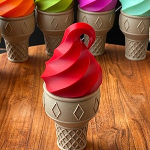 May include: A red ice cream cone with a swirl of ice cream on top. The cone is made of a light brown material and has a waffle pattern.