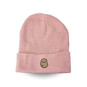 May include: A pink knitted beanie with a brown embroidered potato with a smiling face.
