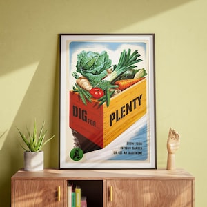 May include: A framed vintage poster featuring a wooden crate overflowing with fresh vegetables, including cabbage, carrots, and tomatoes. The crate has the words "DIG FOR... PLENTY" printed on it. The poster also includes the text "GROW FOOD IN YOUR GARDEN OR GET AN ALLOTMENT."