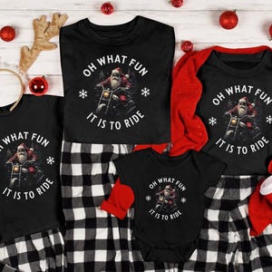 Op de afbeelding: Een set van vier zwarte t-shirts met een witte en rode afbeelding van Sinterklaas op een motorfiets. De tekst op de shirts luidt "Oh What Fun It Is To Ride".