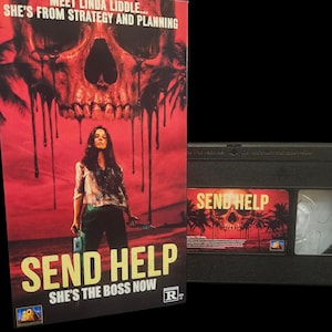 May include: A VHS tape and box set for the movie "Send Help". The box art features a woman standing in front of a skull with dripping blood. The text reads "Meet Linda Liddle... She's from Strategy and Planning" and "She's the Boss Now".