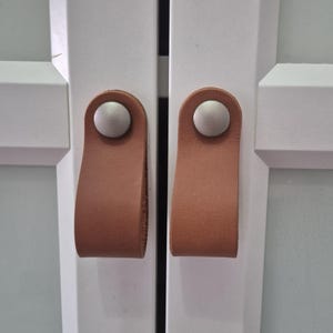 Skåp i vegetabiliskt brunt läder, minimalistiska byråhandtag, fullnarvat loophandtag
