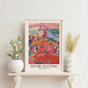 K&ouml;nnte beinhalten: Ein gerahmter Druck eines Gem&auml;ldes von Henri Matisse mit dem Titel "Blick auf Collioure, 1905". Das Gem&auml;lde zeigt eine farbenfrohe Landschaft mit einem roten Haus und einem blauen Meer.