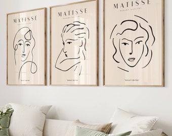 Könnte beinhalten: Drei gerahmte Kunstdrucke mit Strichzeichnungen von Gesichtern. Jeder Druck hat einen beigefarbenen Hintergrund mit schwarzer Strichzeichnung und dem Wort "MATISSE" oben. Die Drucke werden über einem weißen Sofa mit grünen und beigen Kissen angezeigt.