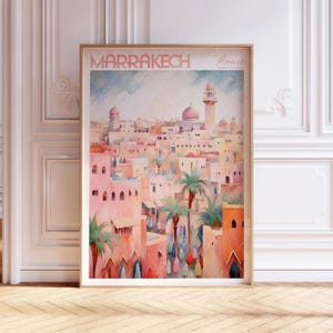 May include: A watercolor painting of a cityscape in Marrakech, Morocco. The painting features a pink and white color scheme and depicts a variety of buildings, including mosques and minarets. The painting is framed in a gold frame.
