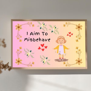 Op de afbeelding: Een ingelijste print met een roze en gele gradiënt achtergrond. De tekst "I Aim To Misbehave" staat boven een cartoon illustratie van een lachend kind in modderige laarzen. Bloemen- en hartmotieven completeren het ontwerp.