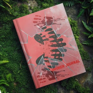 May include: A red journal with a cracked glass effect and a black handprint. The text "BROKEN JOURNAL" is printed on the cover.