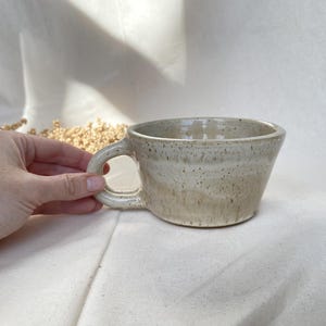 Può includere: Un set di tre tazze in ceramica con finitura opaca e macchiettata. Ogni tazza presenta un colore diverso: azzurro, crema e grigio. Le tazze hanno un design semplice e moderno e un manico comodo.