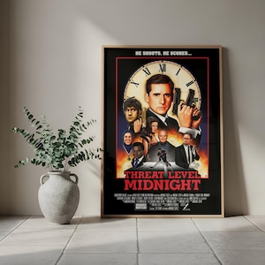 May include: A framed movie poster for "Threat Level Midnight" with a black border. The poster features a central image of a man holding two guns, surrounded by other characters. The title is in red text.