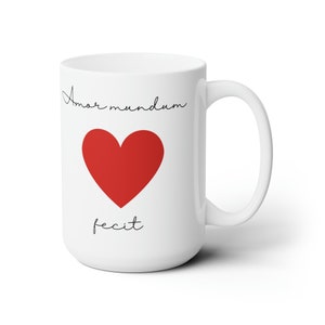 May include: White ceramic mug with a red heart and the text "Amor mundum fecit" in black cursive.
