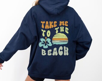 Puede incluir: Una sudadera con capucha azul marino con un gráfico en la espalda que dice "Take me to the beach" con una puesta de sol y una flor.