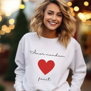 May include: White sweatshirt with a red heart and the text "Amor mundum fecit" in black.