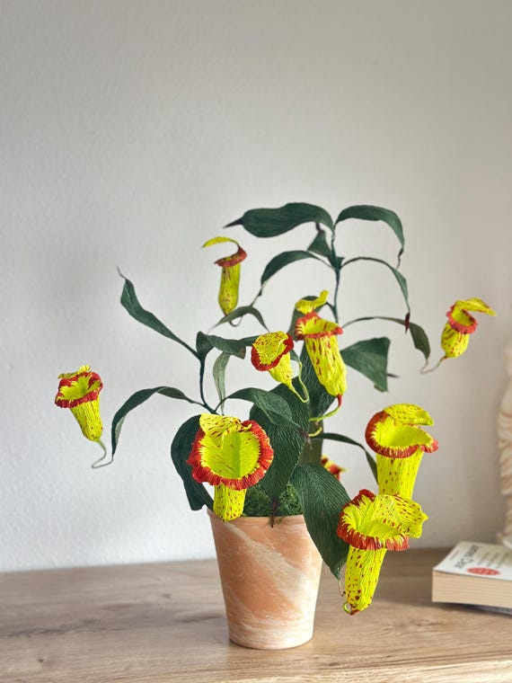 A handcrafted crepe paper replica of a Nepenthes pitcher plant — hauntingly realistic faux carnivorous plant art that requires zero feeding and zero guilt.