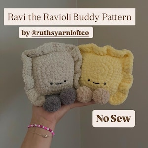 Può includere: Due giocattoli di peluche a forma di ravioli, uno color crema e uno giallo, con facce sorridenti e piedi a pompon grigi e beige. Il testo "Ravi the Ravioli Buddy Pattern" e "No Sew" sono visualizzati. I giocattoli sono tenuti in una mano.