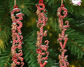 Puede incluir: Tres adornos navideños que deletrean "GRACEY" y "BELIEVE". Cada letra es de rayas rojas y blancas como un bastón de caramelo, decorada con hombres de jengibre, caramelos y acebo.