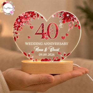 May include: A heart-shaped acrylic plaque with a light-up wooden base. The plaque features red floral graphics, the number 40, and the text "WEDDING ANNIVERSARY", "Anna & David", and "09.09.2026". The design includes small red hearts and glitter accents.