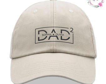 May include: A beige baseball cap with the word "DAD" in a black, outlined font. The names "Sophia" and "Olivia" are below the word "DAD". The number "2" is in the upper right corner of the word "DAD".