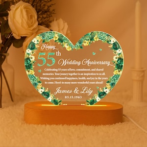May include: A heart-shaped illuminated anniversary plaque with the text "Happy 55th Wedding Anniversary." The plaque is decorated with floral accents and rests on a wooden base. The names "James & Lily" and the date 05.15.1963 are also displayed.