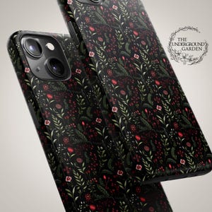 May include: Black phone case with a floral pattern featuring red and green flowers on a black background. The text "THE UNDERGROUND GARDEN" is visible in a white circle.