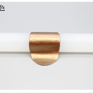 May include: A copper-colored metal clip, curved and rounded, is shown against a white background. The clip is attached to a white cylindrical object. The text "古铜色" is in the upper left corner.