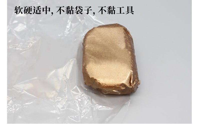 May include: A rectangular object wrapped in gold foil, resting on a crinkled, transparent plastic sheet. The object has a slightly irregular shape and a metallic sheen. Text in Chinese characters is visible.
