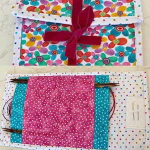 May include: A floral print knitting needle case with a magenta velvet ribbon closure. The case features a white polka dot interior with pockets for needles and accessories. The exterior has a colorful flower pattern with a white border.
