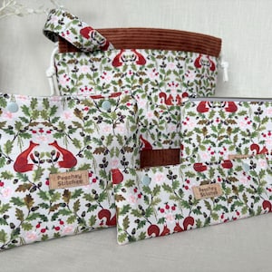 May include: A collection of fabric pouches and a drawstring bag featuring a repeating pattern of red foxes, squirrels, acorns, and green leaves on a white background. Each item includes a tan leather label with the text Peachey Stitches.