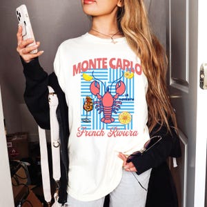 モンテカルロのグラフィックTシャツ、漁師風のロブスターTシャツ、フレンチリビエラのバケーションシャツ、フランス旅行のアパレル、アペロールスプリッツの服
