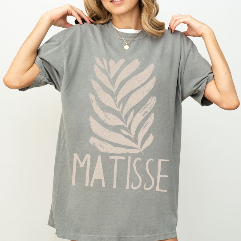 May include: A gray oversized t-shirt with a light brown stylized leaf design and the word "MATISSE" printed on the front.