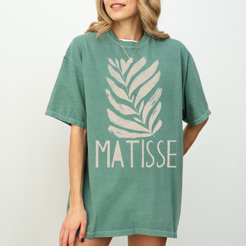 May include: A green t-shirt with a white stylized leaf design and the word "MATISSE" printed on the front.
