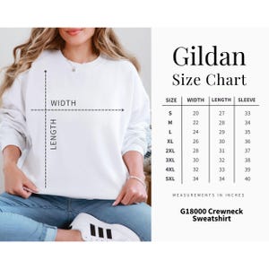 May include: White Gildan crewneck sweatshirt with a size chart. The chart shows measurements in inches for width, length, and sleeve length, ranging from size small to 5XL. The sweatshirt is G18000.