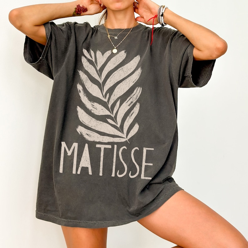 May include: A dark gray oversized t-shirt with a white stylized leaf design and the word "MATISSE" printed on the front.
