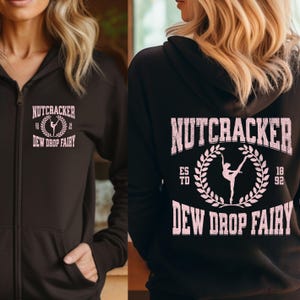 May include: A black zip-up hoodie with the text "NUTCRACKER" above a ballerina graphic and "DEW DROP FAIRY" in pink. The back of the hoodie repeats the text and graphic with "ESTD 1892".
