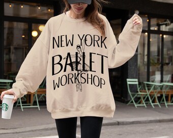 Puede incluir: Una sudadera beige con el texto "NEW YORK BALLET WORKSHOP" y una silueta negra de una bailarina con un tutú blanco.