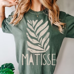 May include: A green t-shirt with a white stylized leaf design and the word "MATISSE" printed on the front.